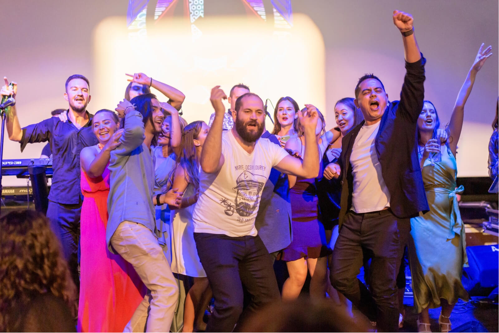 The Atolye15 Team dancing on stage with their fists in the air at their 10th-year party.