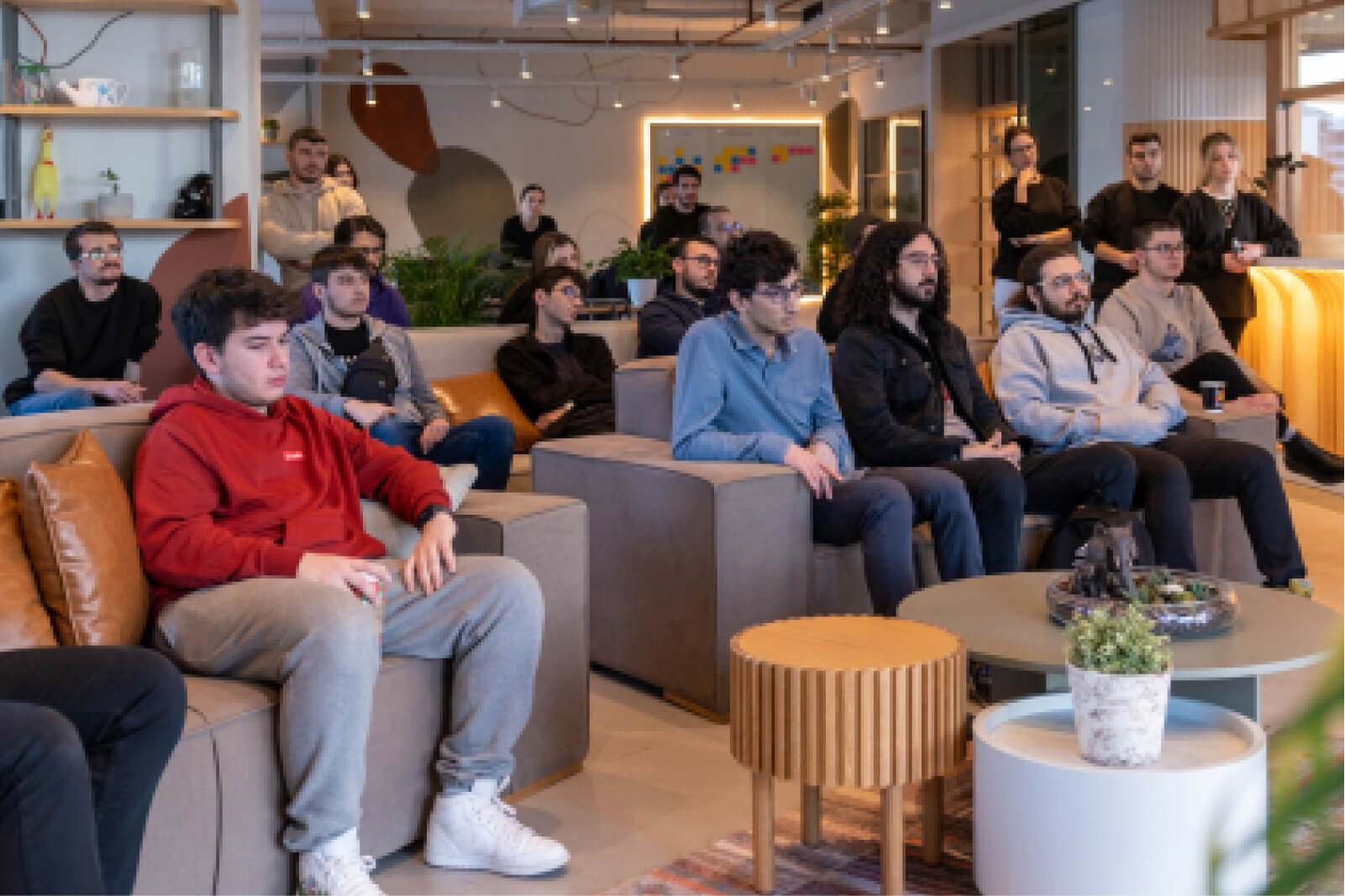 A group of young men sitting on grey couches and white and wooden coffee tables in Atolye15’s Izmir office.