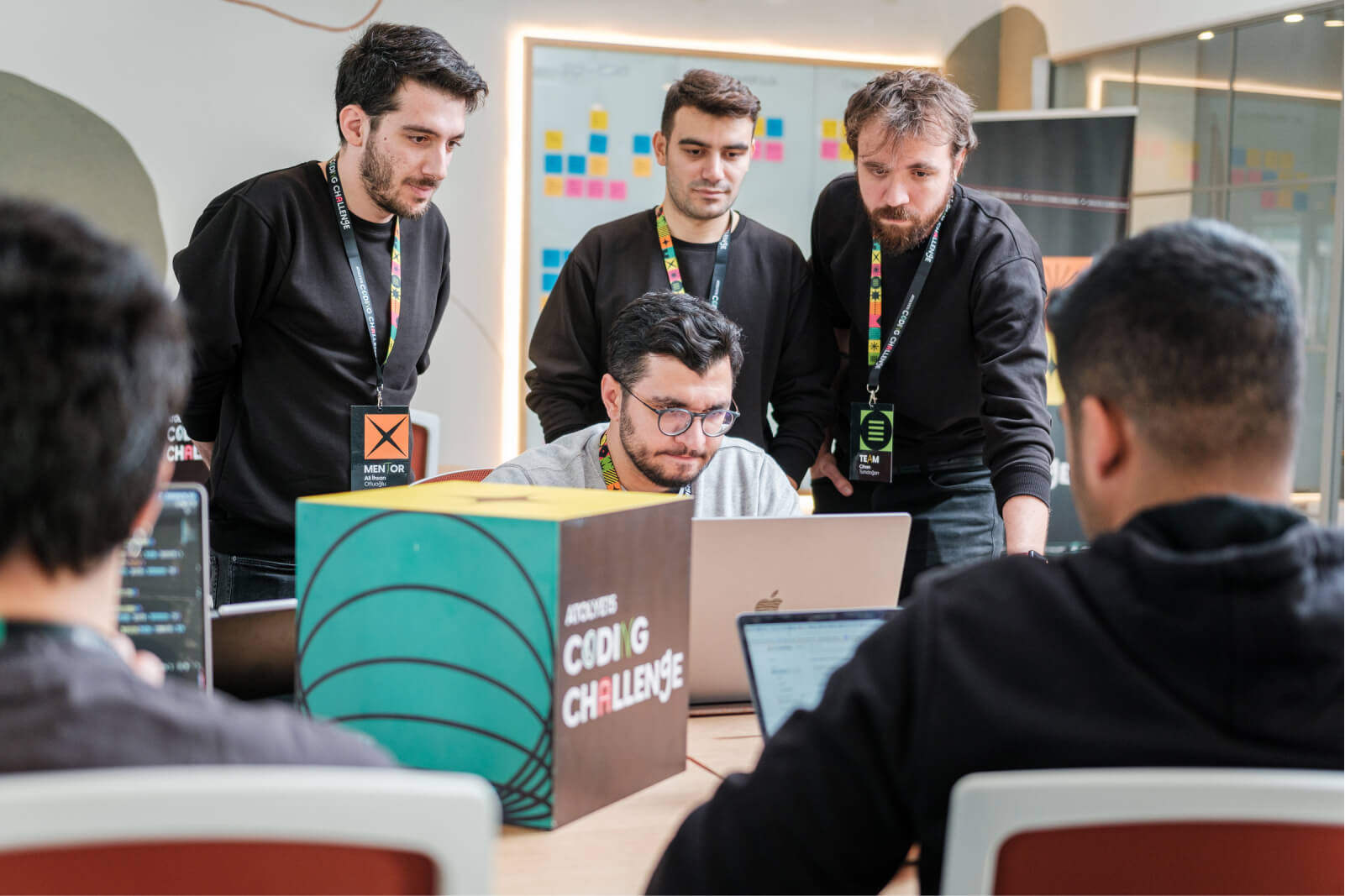 A group of men working in an office and looking at a laptop during Atolye15’s Coding Challenge Izmir event.