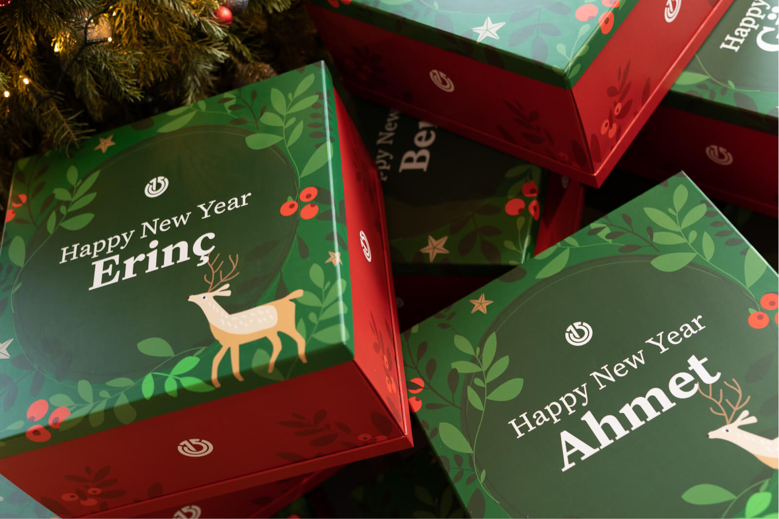 A pile of red and green Christmas gift boxes that say “Happy New Year Erinç” and “Happy New Year Ahmet.”