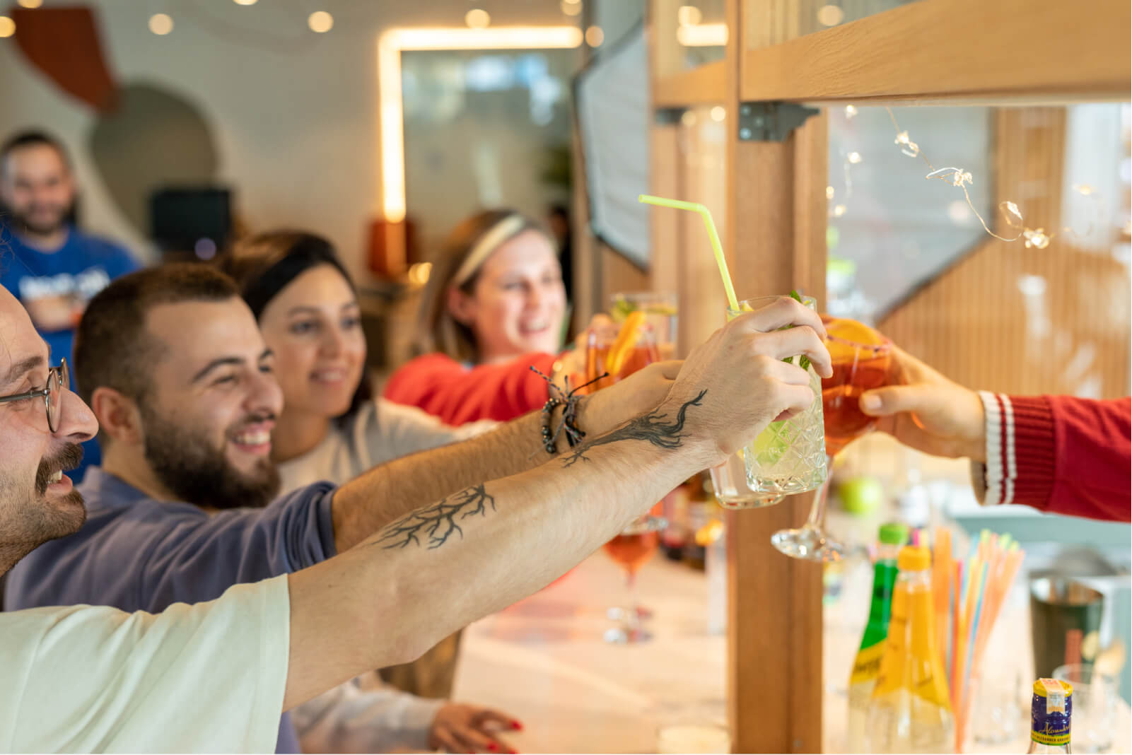 A group of people smiling and raising their cocktail glasses over a kitchen counter at Atolye15’s İzmir office.