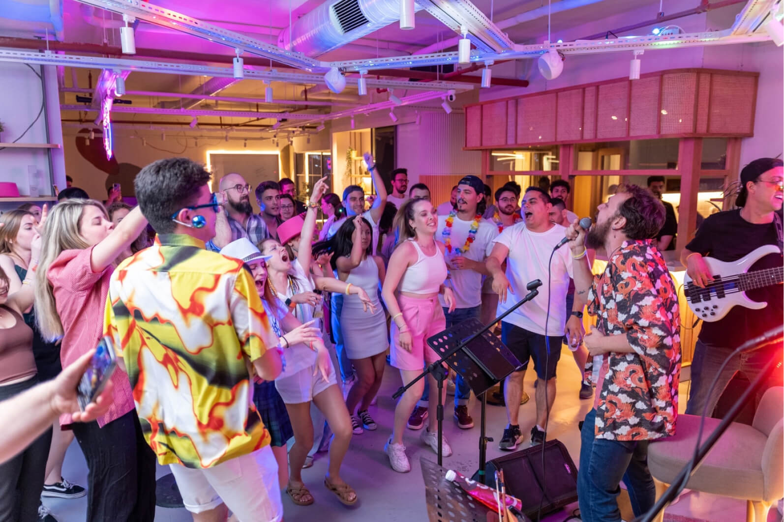 People dancing at Atolye15’s İzmir office and watching a male singer holding a microphone and a man playing the guitar.
