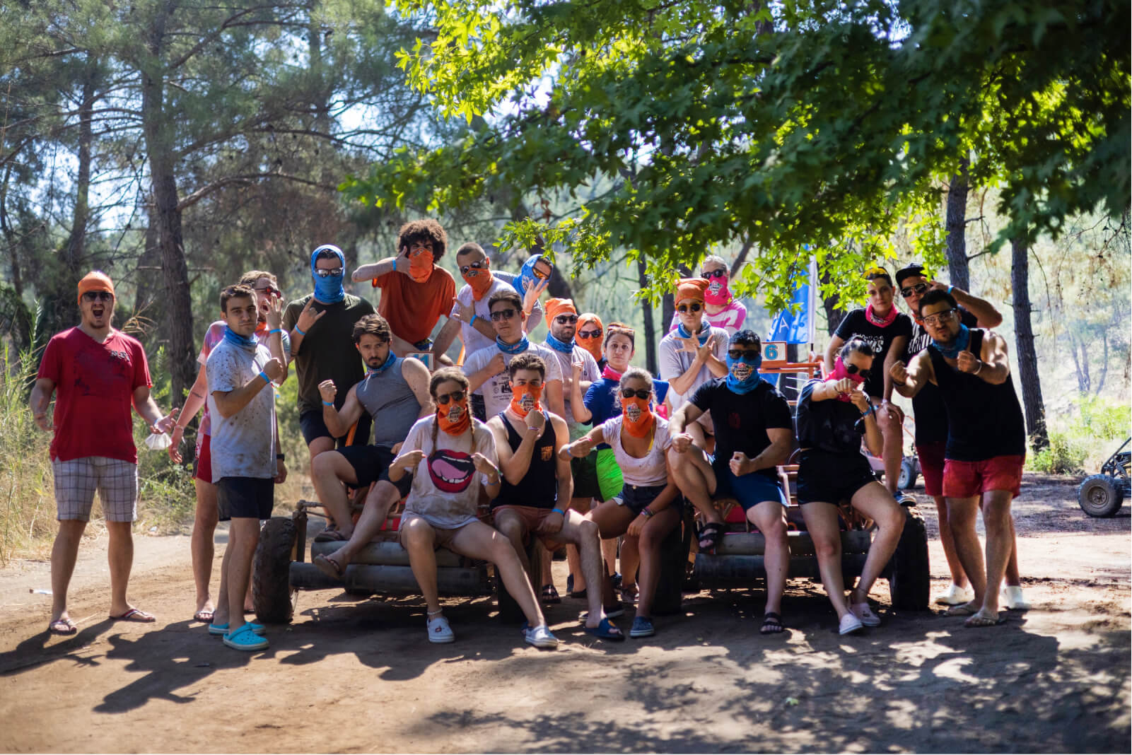 The Atolye15 Team showing off their muscles and fists while wearing face masks in a forest during Summer Retreat’22.