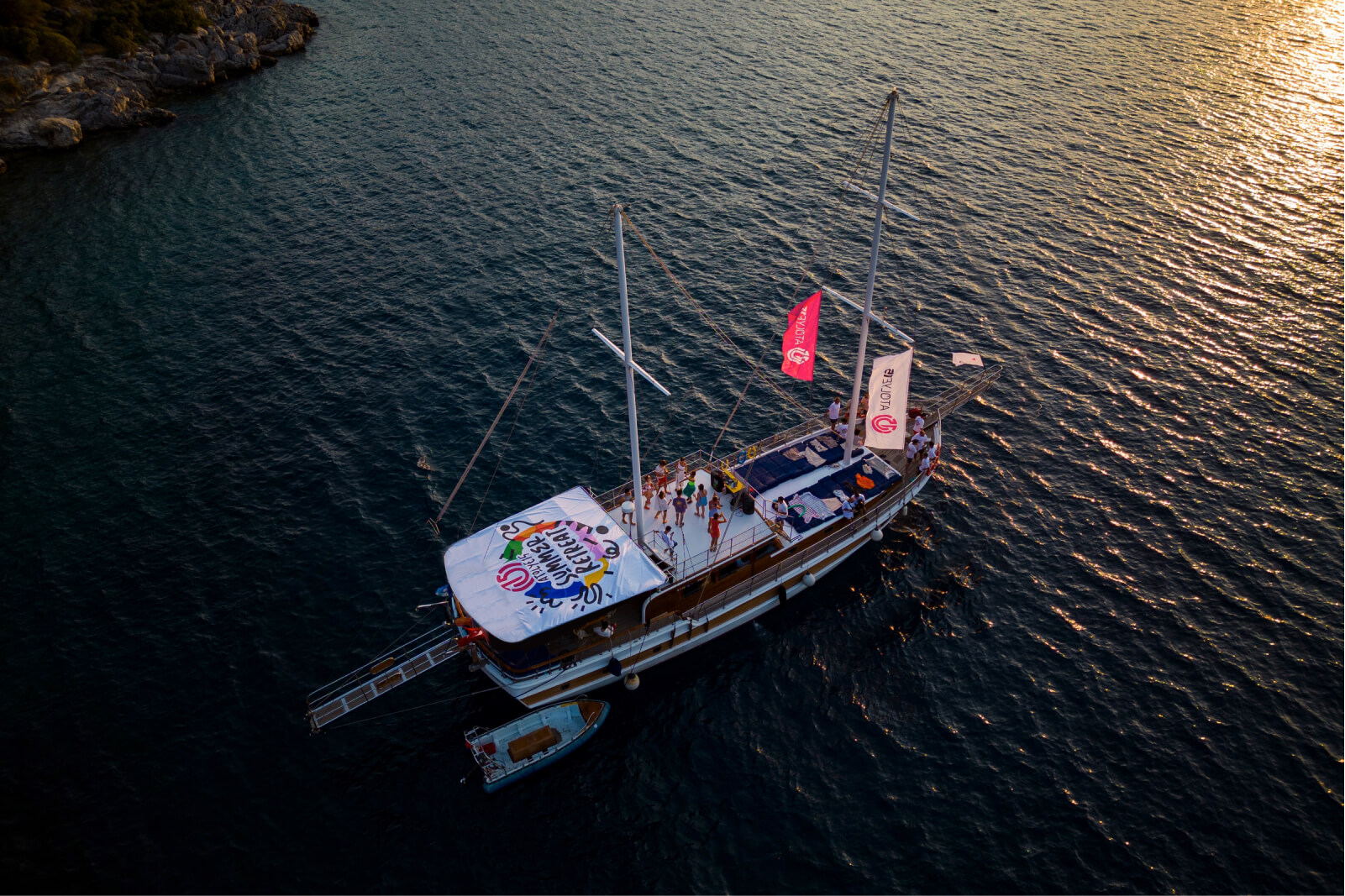 A group of people partying on a boat with the Atolye15 logo banners and Summer Retreat flags out in the sea.