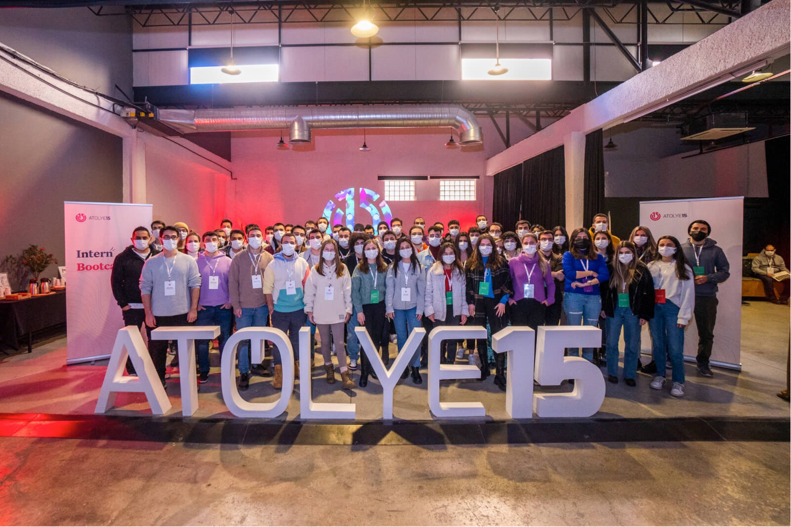 A group of people, standing behind a white Atolye15 letter statue and a banner that says “Intern Bootcamp.”