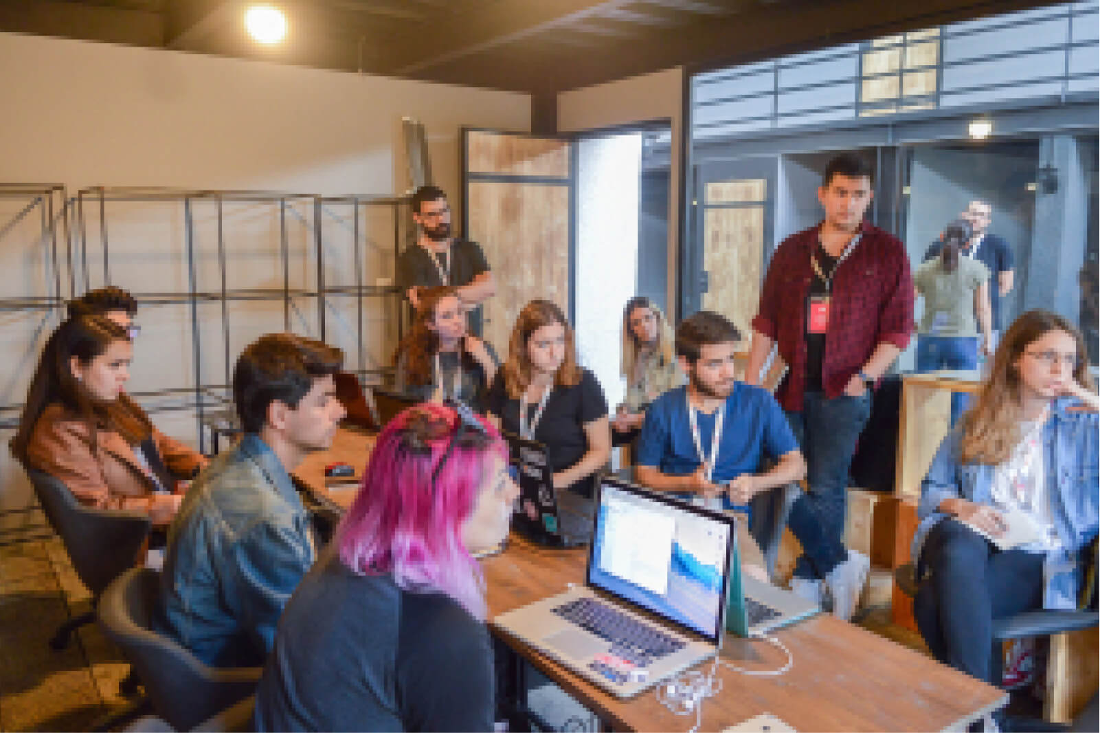A group of young people gathered around a table with a laptop at the third Atolye15 Internship Bootcamp.