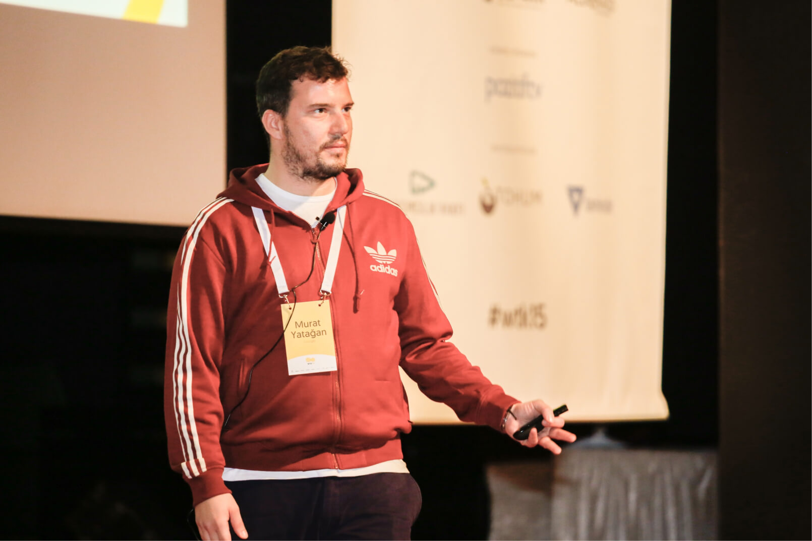 A man in a red Adidas sweatshirt wearing a yellow name tag that reads “Murat Yatağan” giving a presentation at WTK’15.