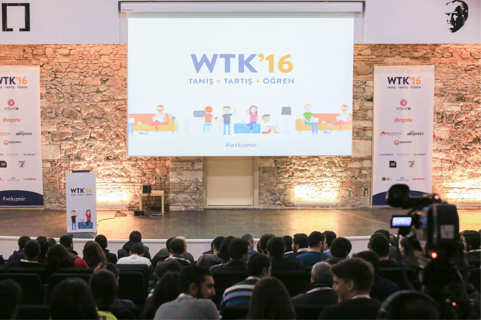 A conference hall filled with people and a presentation screen saying “WTK’16 Tanış, Tartış, Öğren” next to an Atolye15 logo.