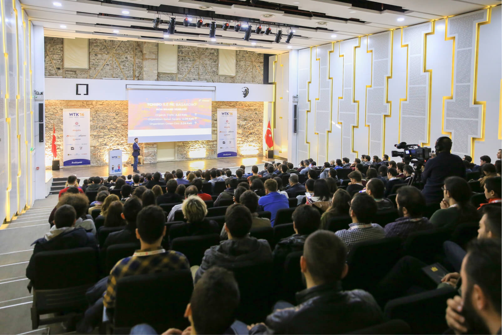 A man giving a presentation in front of a large crowd of people at the WTK’16 tech conference by Atolye15.