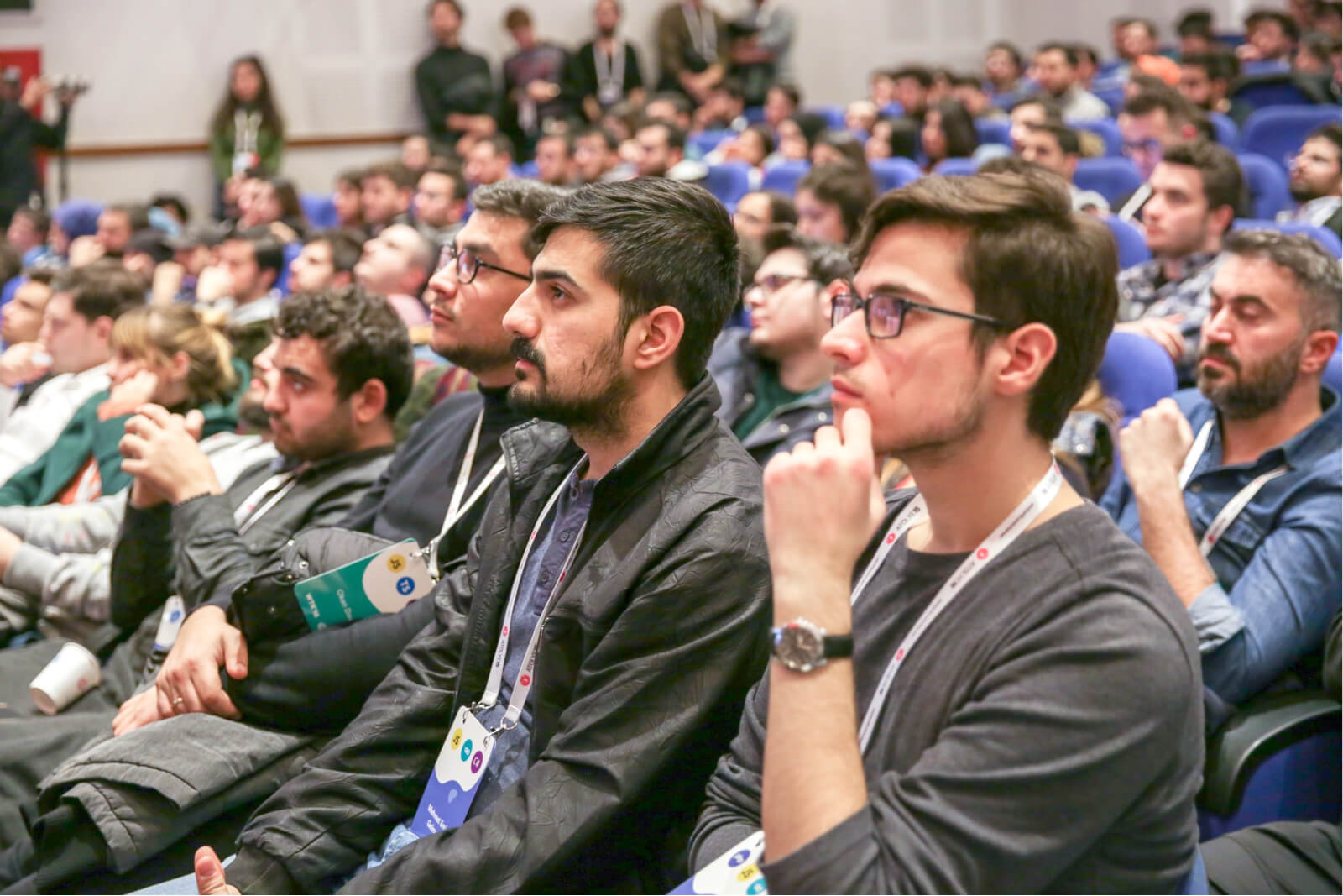 A crowd of people sitting in a conference hall and looking ahead.