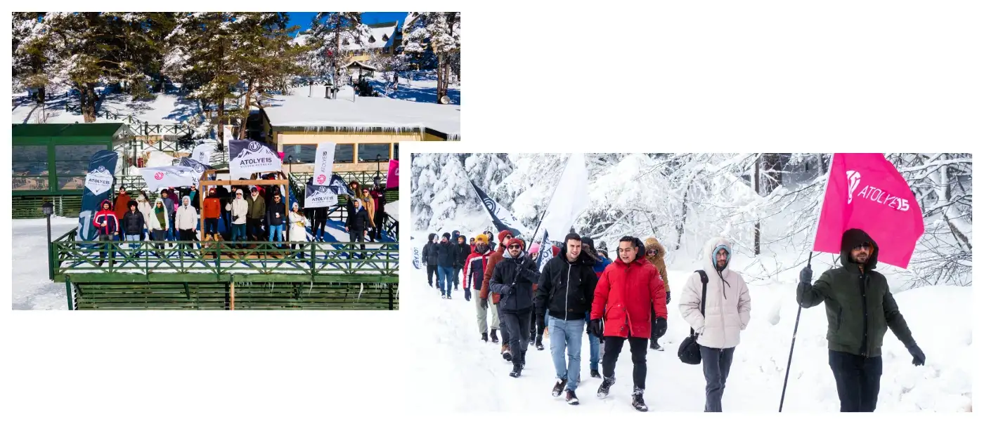 A group of people in winter coats walking in the snow carrying an Atolye15 flag and posing by the frozen Abant lake.