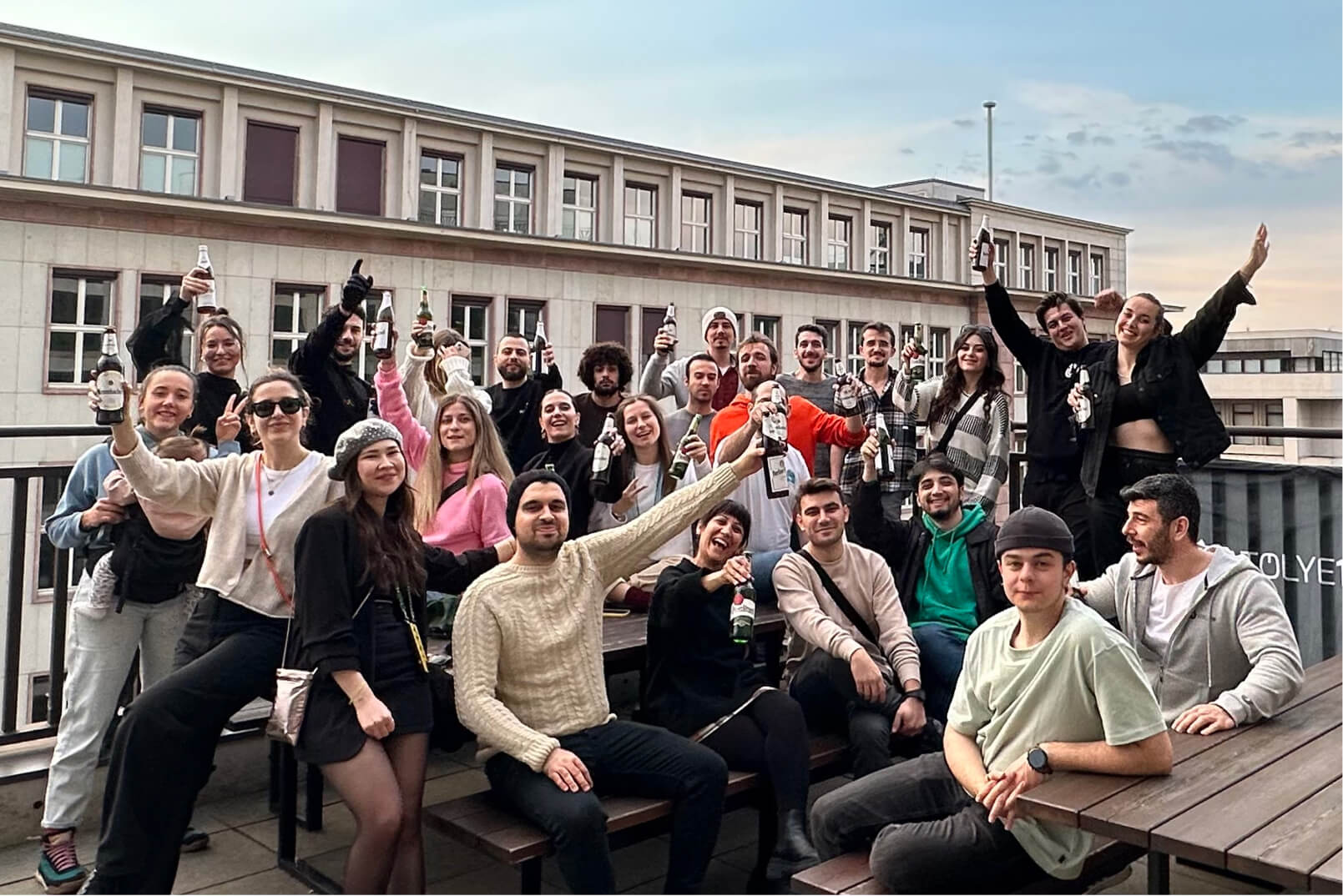 The Atolye15 Team raising their beer bottles on a terrace in celebration of their new Berlin office.