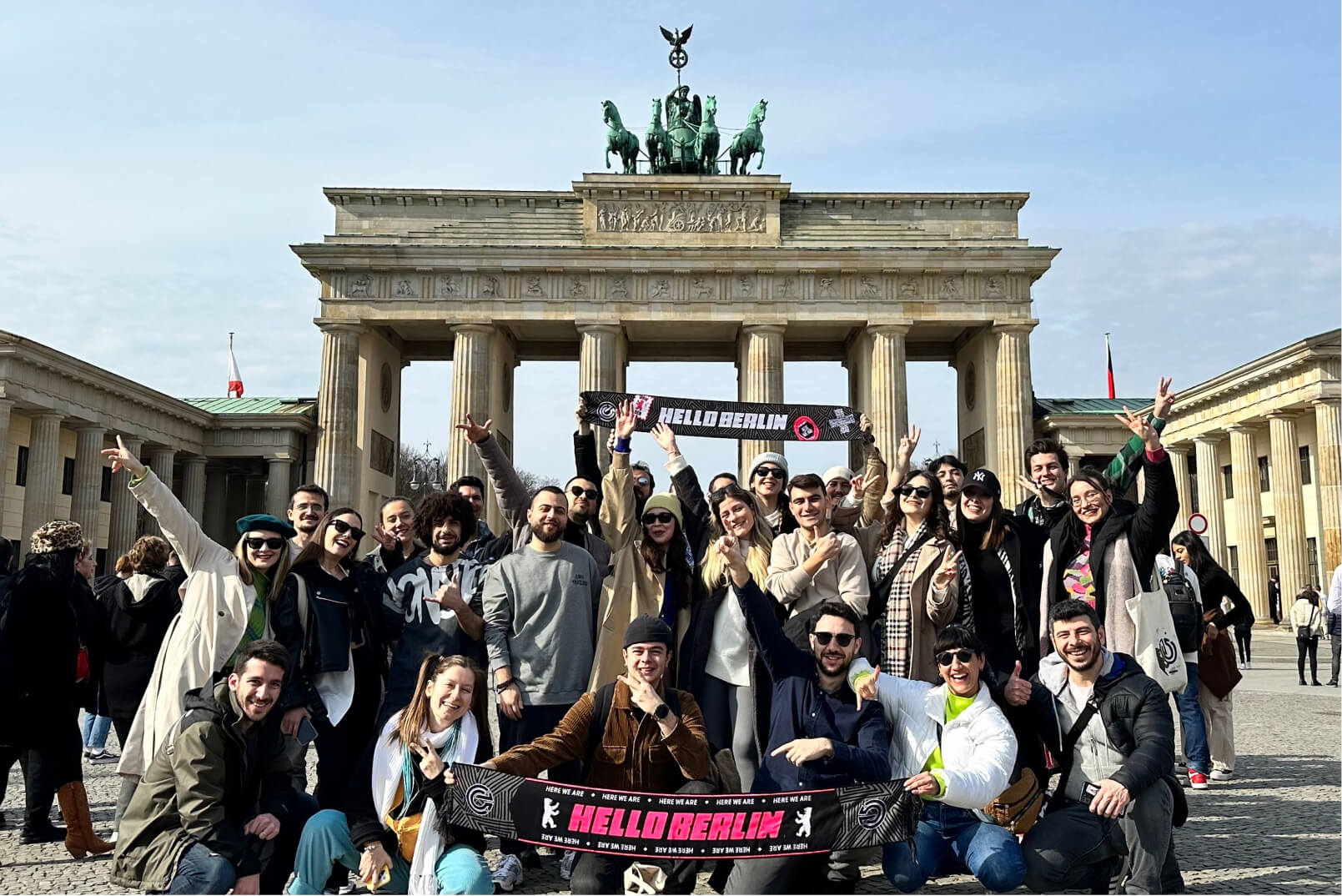 Atolye15 employees holding “Hello Berlin”' scarfs in front of Brandenburg Gate.