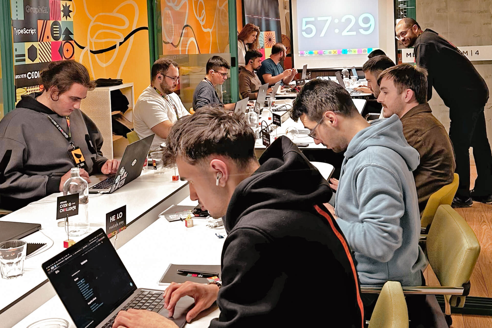 Atolye15 Coding Challenge Ankara participants gathered around a desk, developing their projects with a countdown screen in the background.
