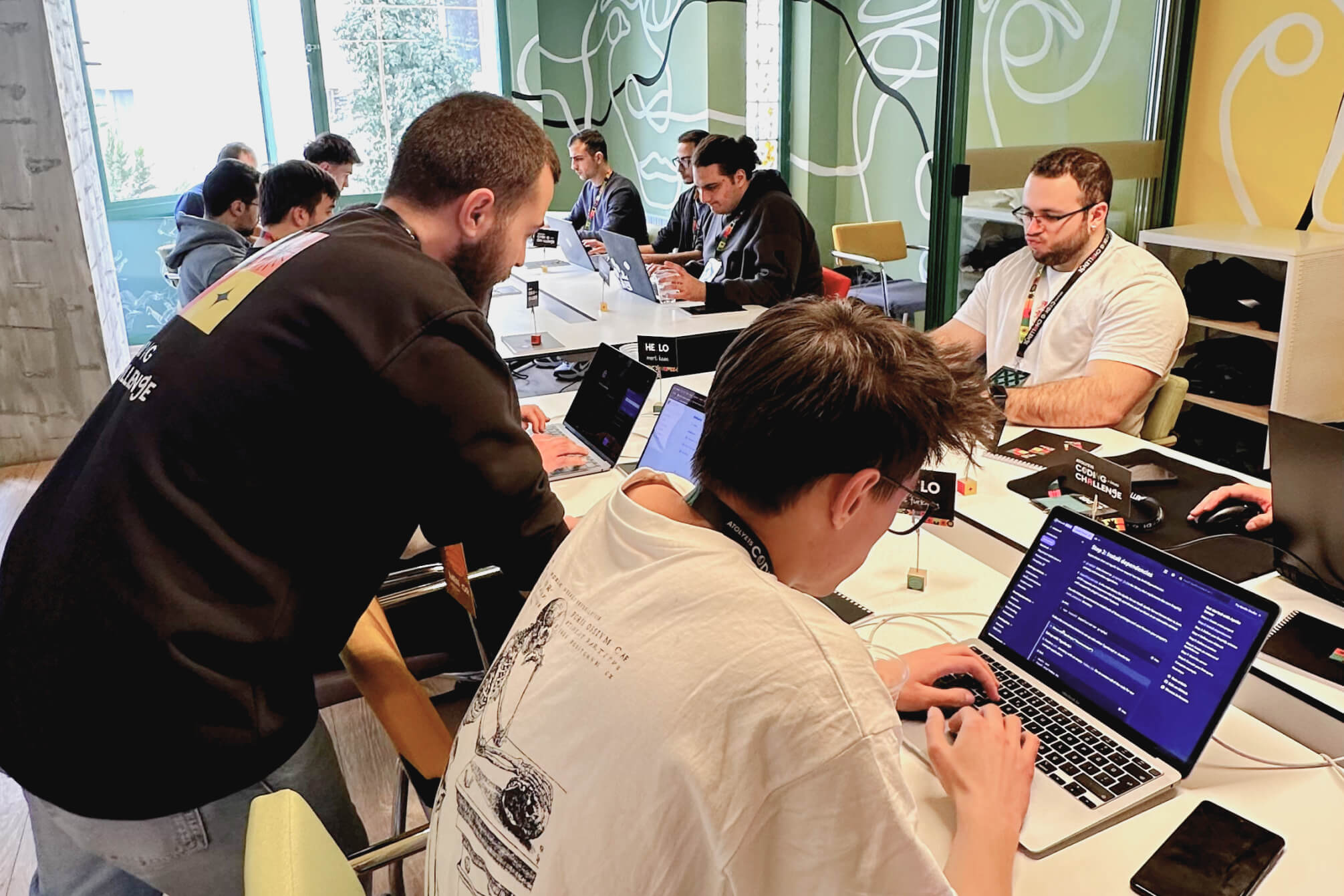 Atolye15 Coding Challenge Ankara participants gathered around a desk, coding on their laptops.