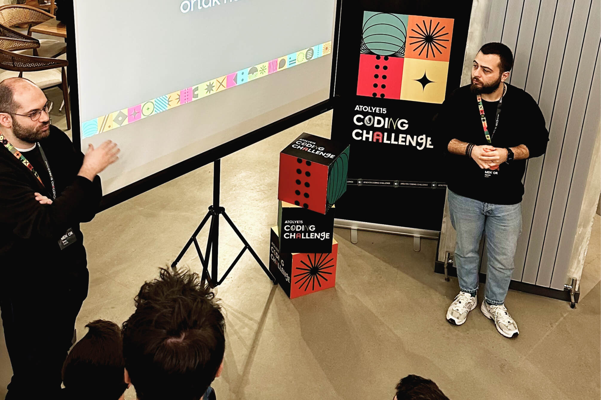 Erinç Fırtına, the lead frontend developer, and, Alpcan Aydın, the CTO of Atolye15, standing next to an Atolye15 Coding Challenge banner and giving a presentation.