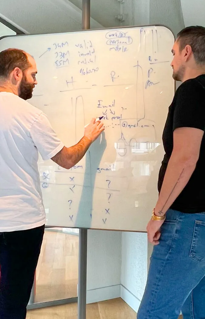Two professionals discussing over a whiteboard with email validation flow.