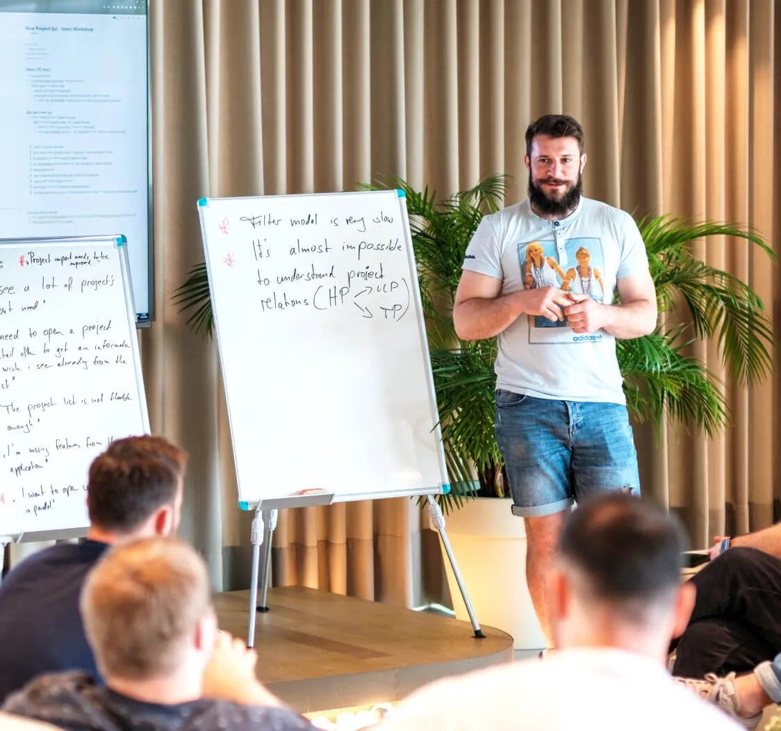 Man presenting at a workshop with a whiteboard and project notes.