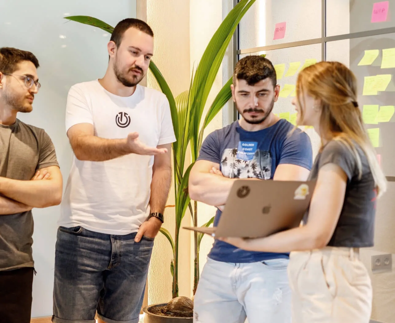 Team members in a discussion by a window with post-it notes in the background.