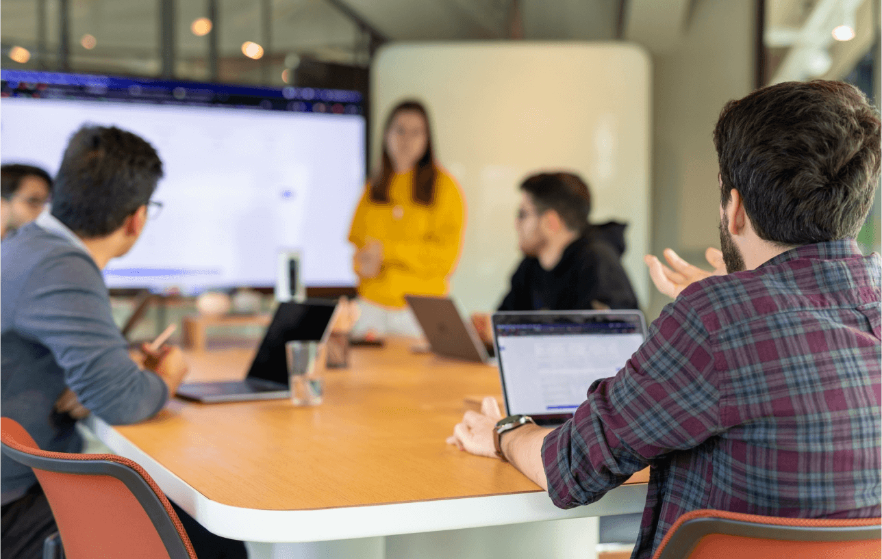 Group of professionals in a meeting with a presentation in the background.