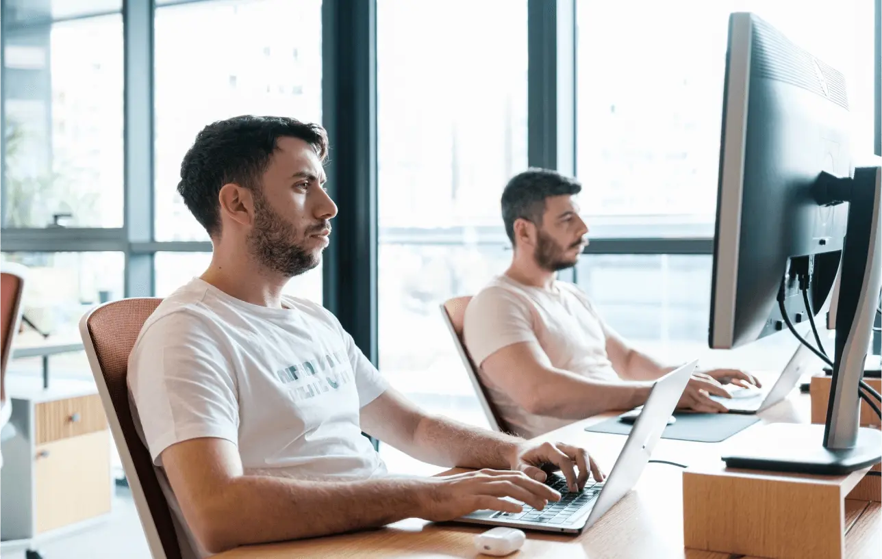 Two men working on computers in a modern office setting.