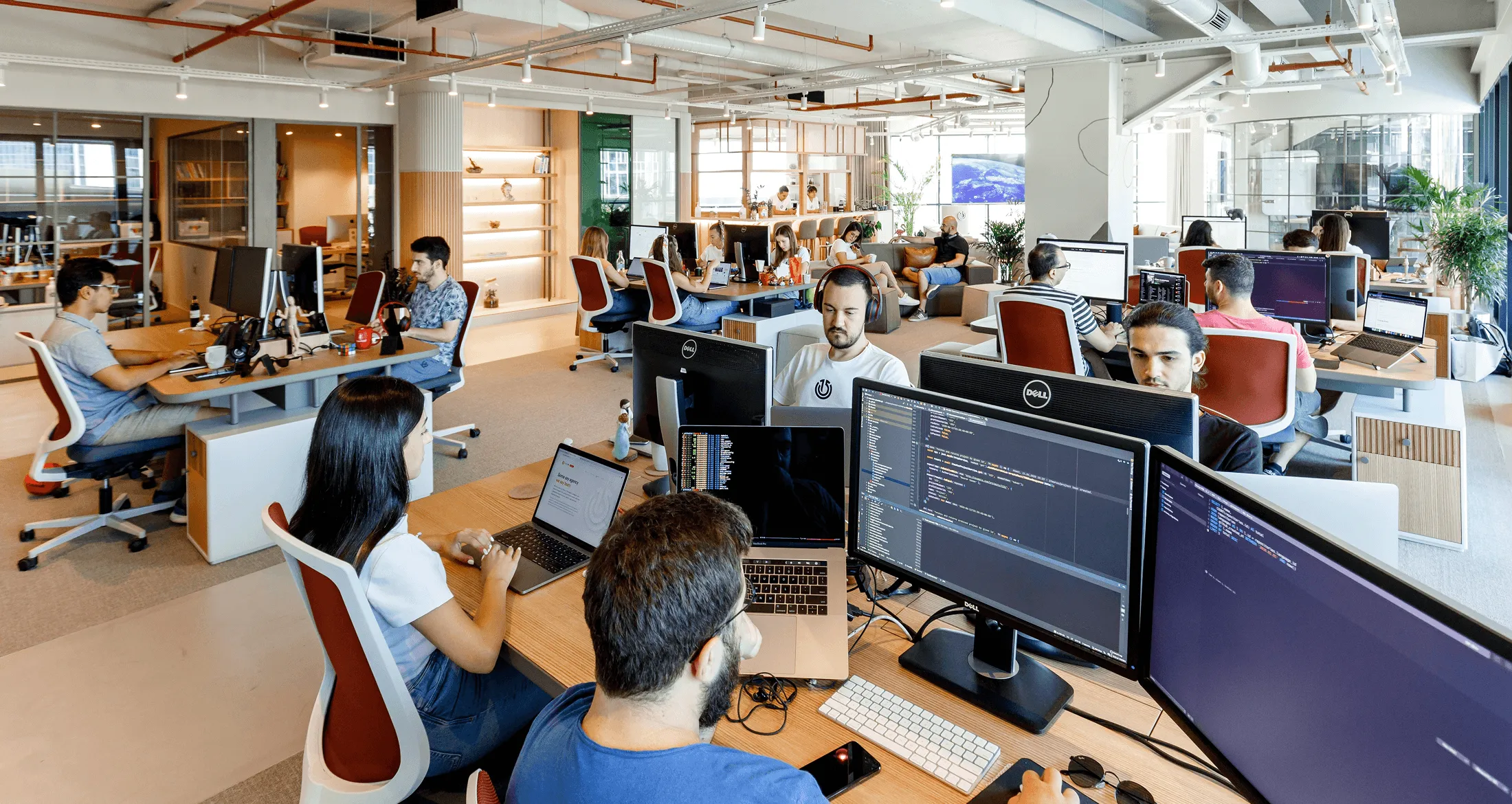 A group of five people chatting and laughing in a modern office.
