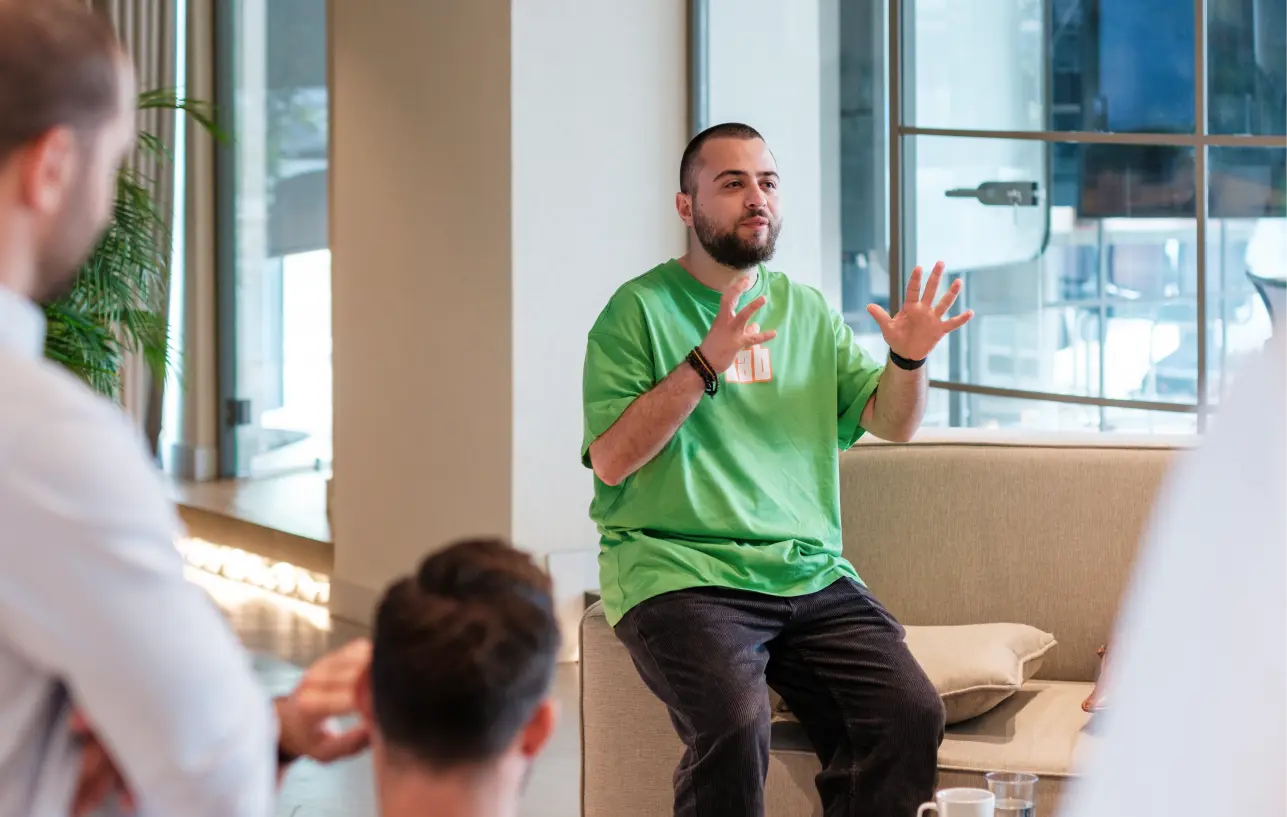 Team member leads a discussion while seated on a sofa, using hand gestures during a collaborative session.