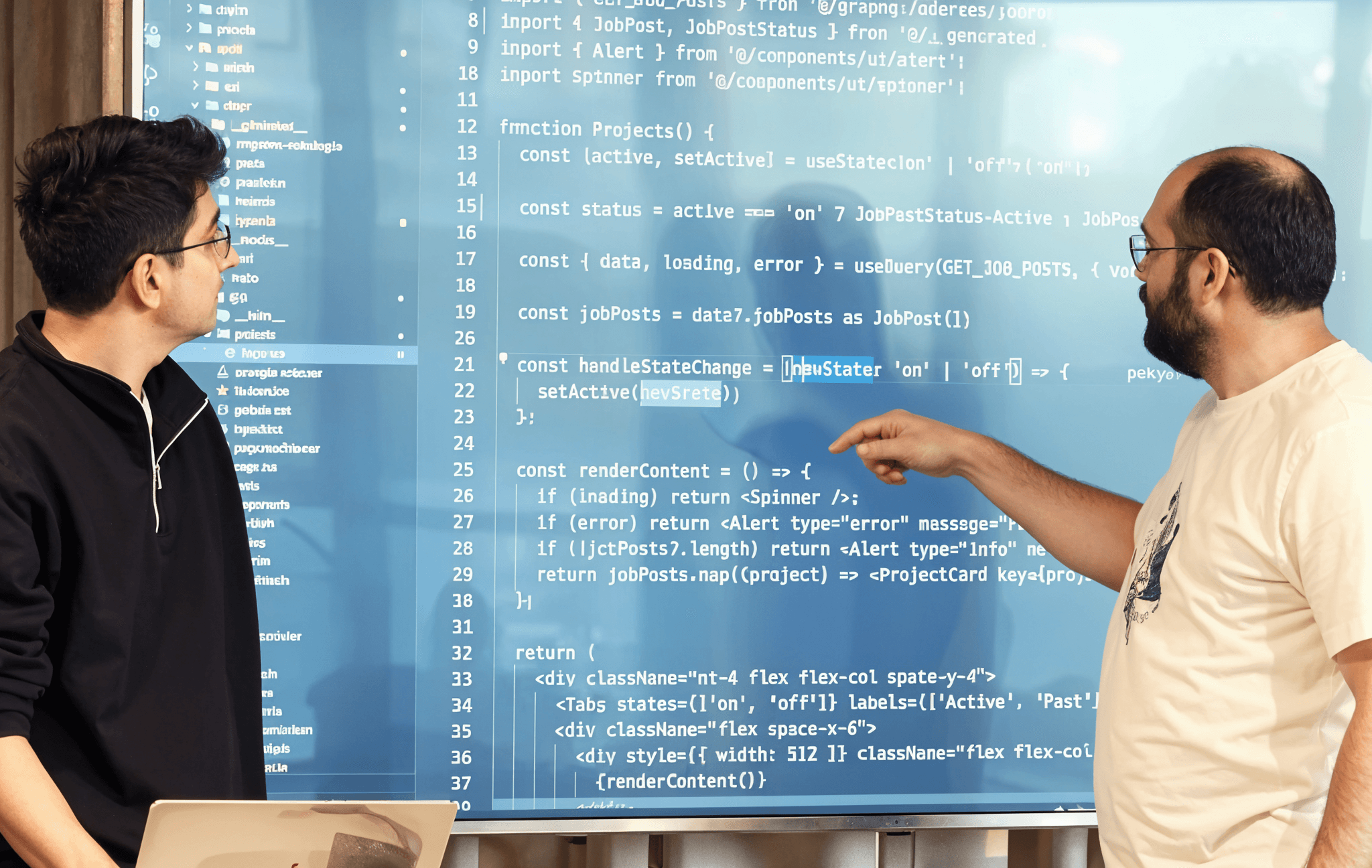 Two developers reviewing code on a large screen, discussing implementation details.