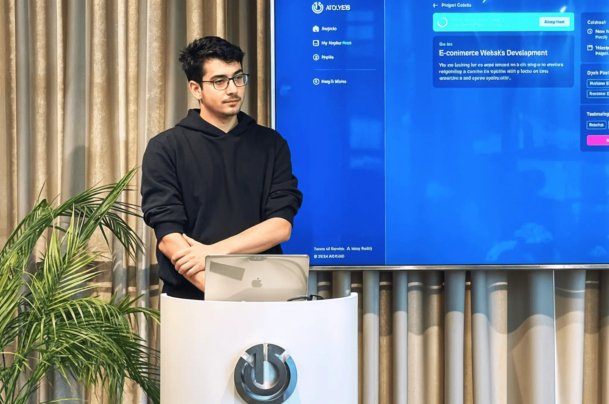 Developer presenting a project at a podium with a laptop in front of a large screen.