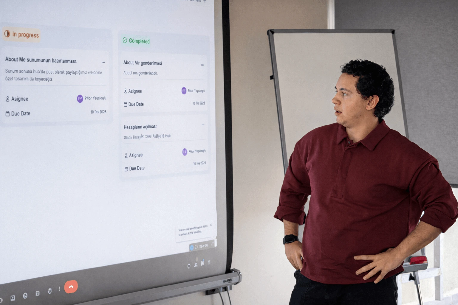 A presenter reviewing project tasks on a large digital screen during a Next Talent 2 demo session, explaining progress and completed items to the room.